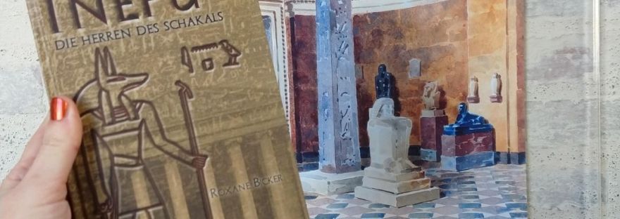 Eine Hand hält das Buch Inepu. Im Hintergrund eine Auquarellzeichnung der historischen Räume der Glyptothek.